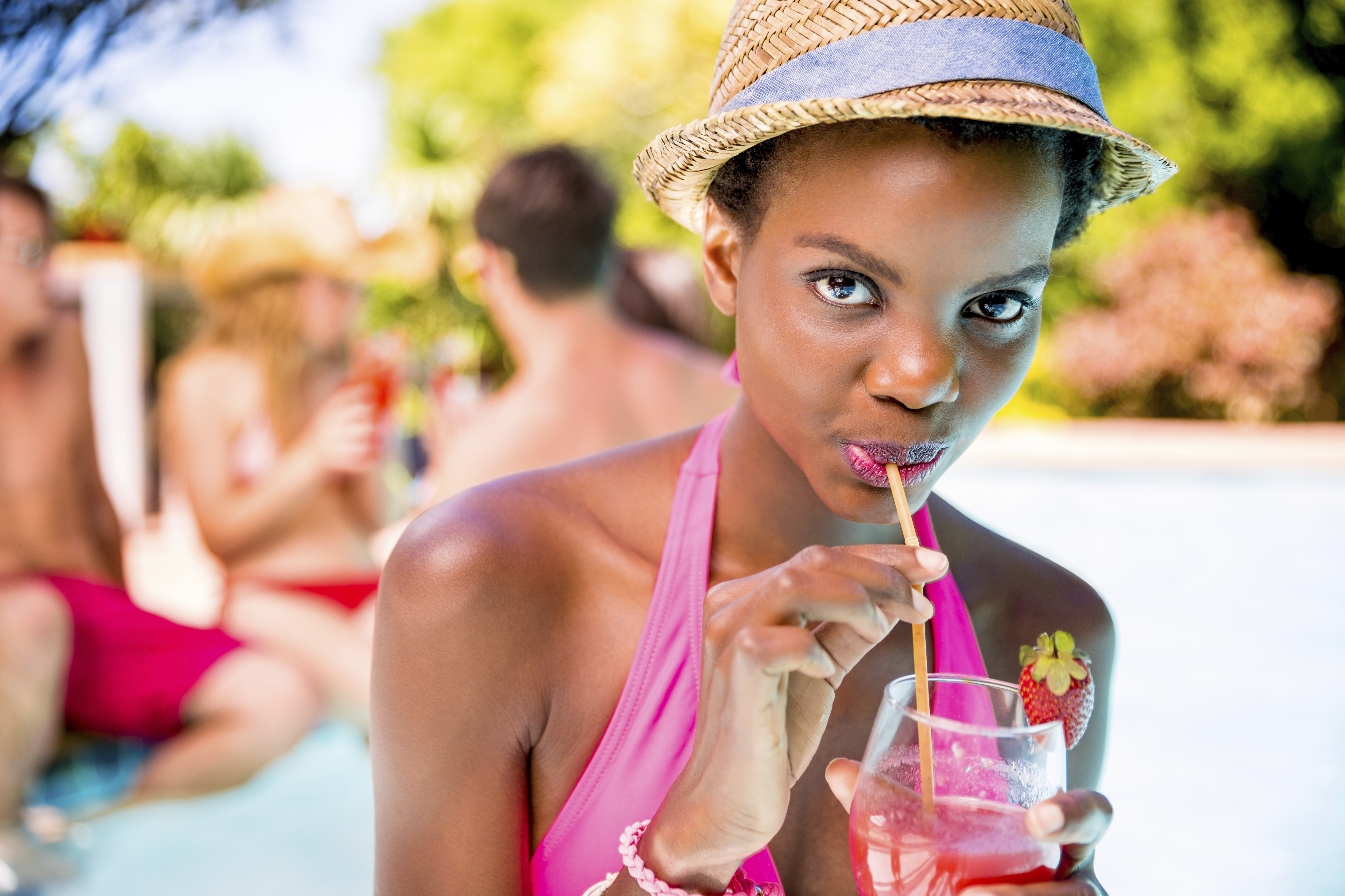 African american woman drinking cocktail simming pool