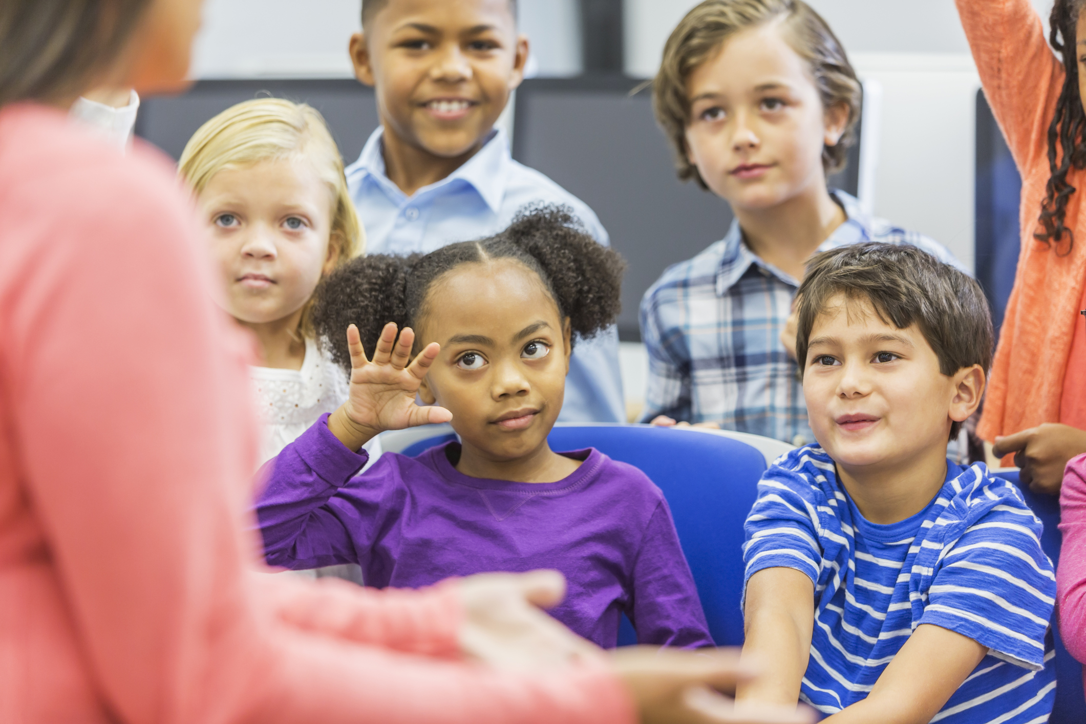 Multi-ethnic group of children, girl raising hand