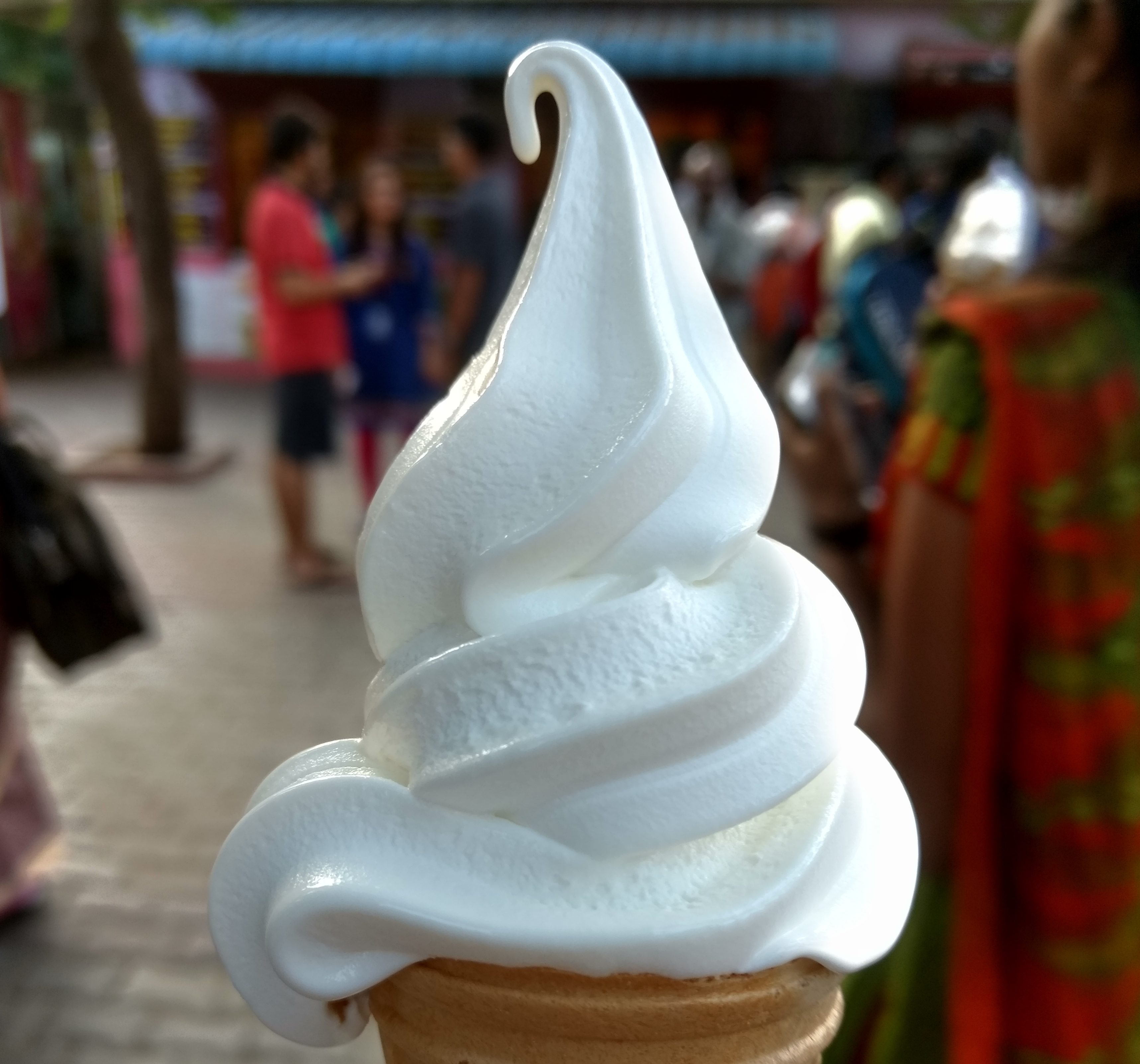 Close-Up Of Ice Cream Cone With People In Background