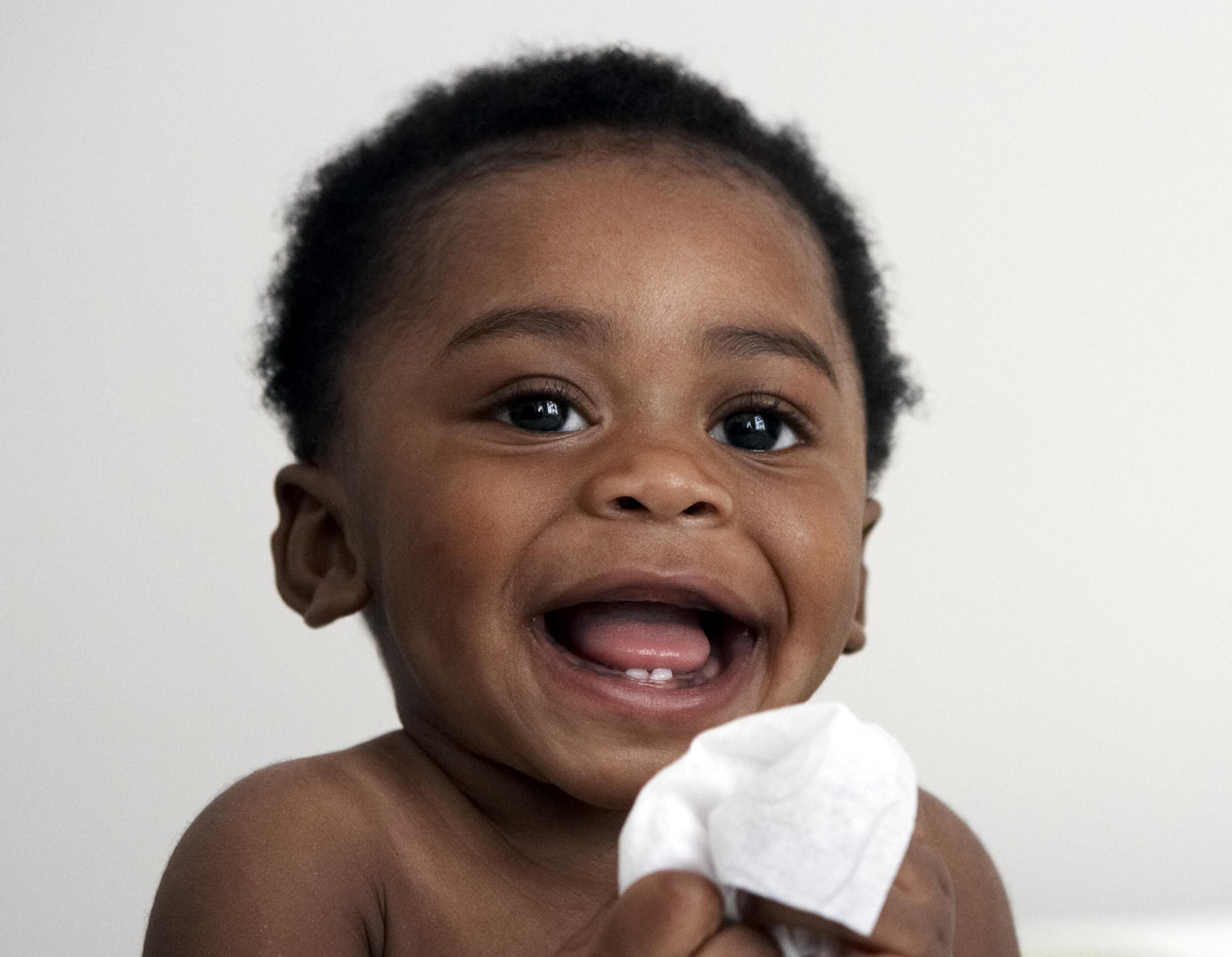 baby holding wipe smiling