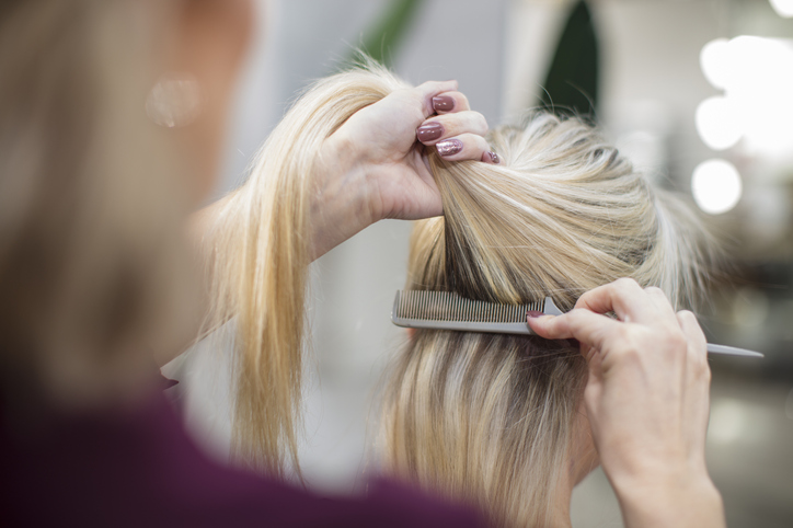 Hairdresser styling customer's hair in salon