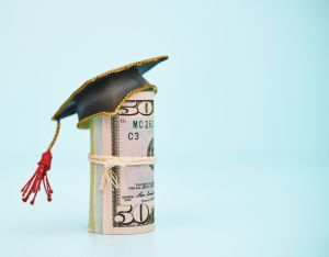 Cost of Education. Money roll wearing a mortarboard graduation cap