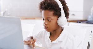 Child, boy or headphones for distance learning on laptop in house for remote education, homeschool or Nigerian lockdown study. Thinking, kid or student youth on technology streaming classroom webinar